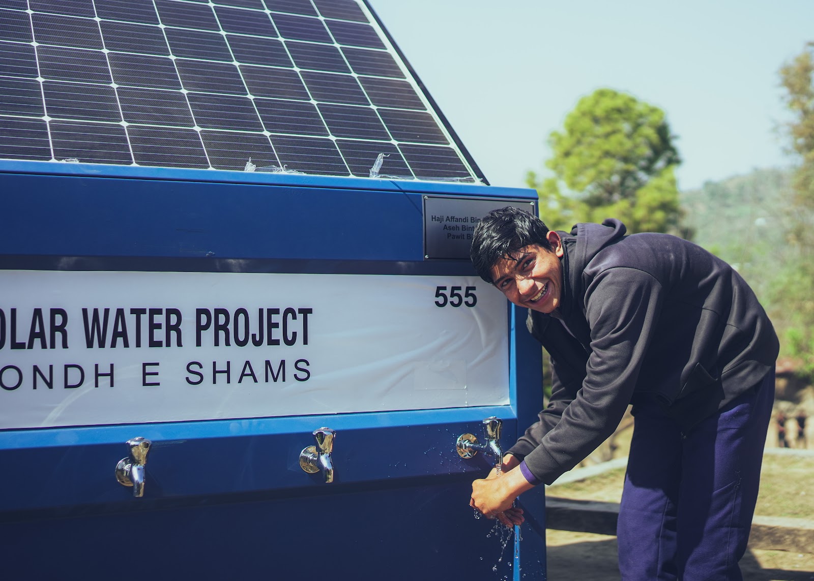 A young man drinking clean water from an OASIS Box tap